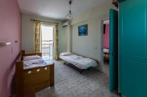 a small room with two beds and a window at Vossos Hotel Apartments in Laganas