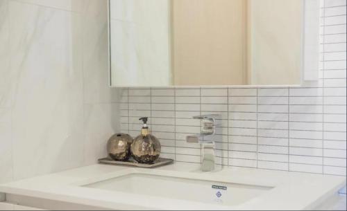 a bathroom sink with a mirror and two vases on it at Stylish Luxury 1 Bedroom, Hyde Sukhumvit 11, Near BTS Nana & Asok in Bangkok
