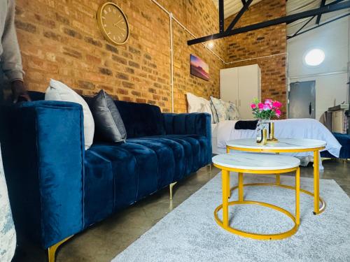 ein Wohnzimmer mit einem blauen Sofa und einem Tisch in der Unterkunft Blue Haven on Craftmanship Hotel with WiFi Pool & Parking in Johannesburg