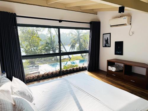 a bedroom with a large window with a view of a pool at Nuraai River Chalets in Ambalangoda