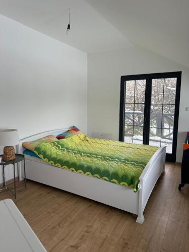 a bed with a green blanket on it in a room at Vikendica Dedovina selo Negrišori-Lučani in Lučani