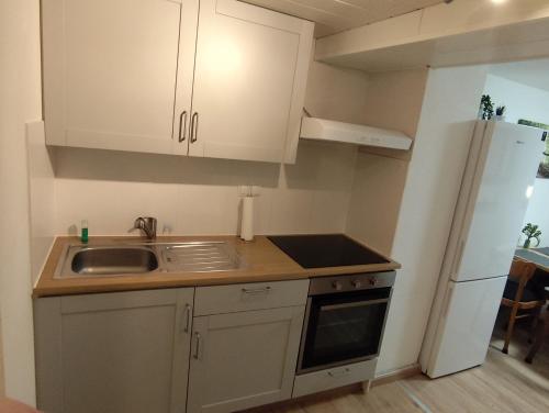 a kitchen with white cabinets and a sink and a refrigerator at FeWo Hospitalskapelle in Schwalmstadt