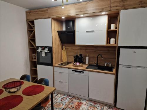 una cocina con armarios blancos y una mesa con mesa en Apartman Miki, en Vlašić