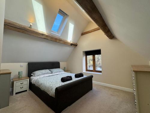 a bedroom with a bed and two windows at Woodland Forge - The Stables in Over Whitacre