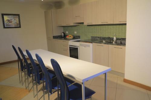 cocina con mesa blanca y sillas azules en Kora Hotel Suites, en Addis Ababa