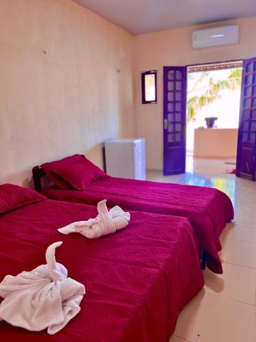 two beds with towels on them in a bedroom at Pousada Brisa Mineira in Cascavel