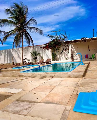a swimming pool in front of a house with a palm tree at Pousada Brisa Mineira in Cascavel