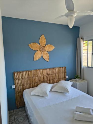 een bed met een blauwe muur waarop een bloem is afgebeeld bij Pousada Guarda do Embaú in Guarda do Embaú