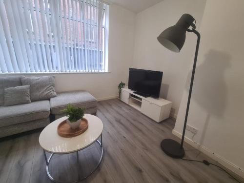 a living room with a couch and a table and a lamp at Pudding Chare Apartments in Newcastle upon Tyne