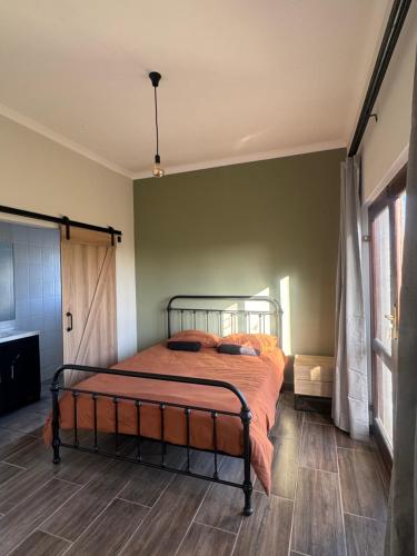 a bedroom with a bed with an orange comforter at Sea and Vlei on Disa in Bettyʼs Bay