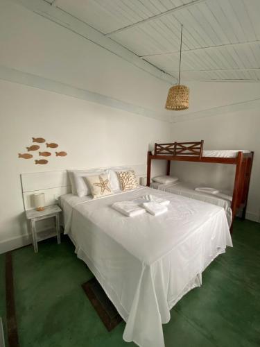 a bedroom with a large white bed with a table at Pousada Quintal da Praça in Prado