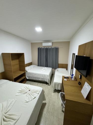 a hotel room with two beds and a flat screen tv at Isadora Pousada in Salinópolis