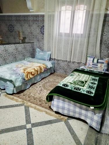Appartement في Benguerir: غرفة نوم بها سريرين ونافذة