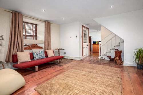 een woonkamer met een rode bank en een trap bij The Old Bakehouse - Group Getaway in Llandysul