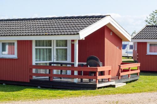 a red cottage with a porch and a deck at Rømø familiecamping in Rømø Kirkeby