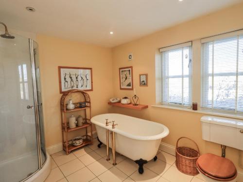 a bathroom with a tub and a shower and a sink at Orchard House in Leyburn