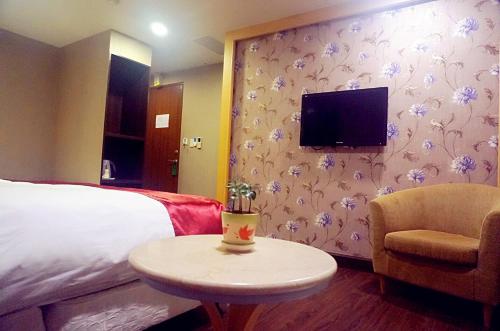 a hotel room with a bed and a table and a tv at Every Day Hot Spring Hotel in Jiaoxi
