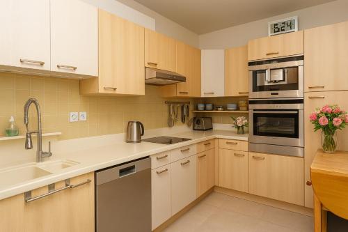 a kitchen with wooden cabinets and stainless steel appliances at Appartement Premium 100 m2 avec Jardin Privé Plage et Centre à 400 m in Deauville