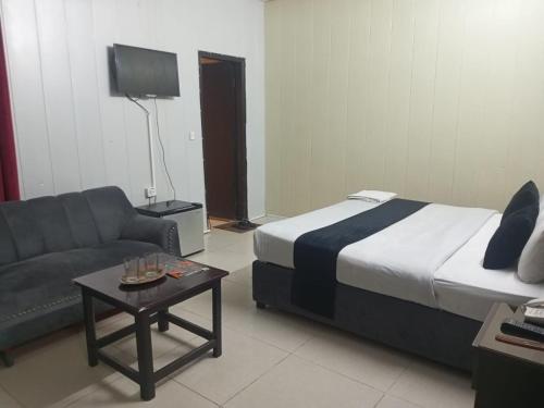 una camera da letto con un letto, un divano e un tavolo di Hotel The Tulip a Lahore