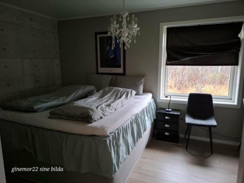 a bedroom with a bed and a chair and a window at Mettes holiday home in Silsand
