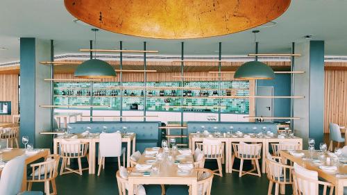 a restaurant with tables and chairs and a bar at Pedras do Mar Resort & Spa in Fenais da Luz