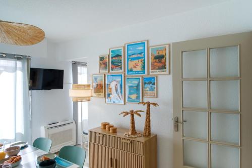 a room with a table and some pictures on the wall at Maïmo Cosy Appartement rénové Centre Ville 300m plage, Clim, Parking in Sainte-Maxime