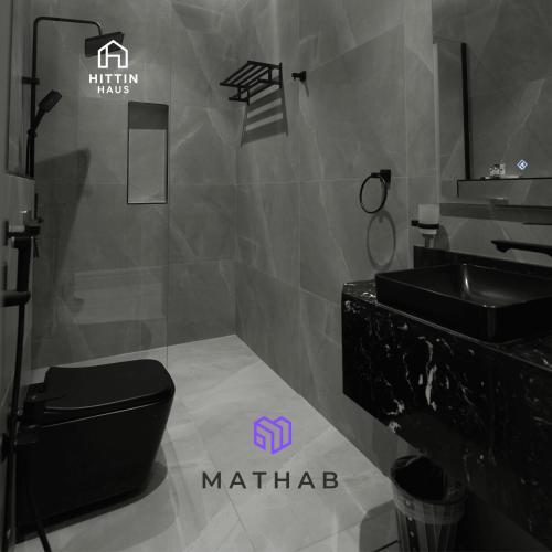 a bathroom with a black toilet and a sink at Hittin Haus in Riyadh