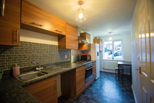 een keuken met houten kasten, een wastafel en een raam bij Long Barn House - Andover in Enham-Alamein