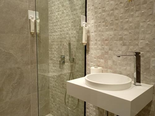Un baño con lavabo y ducha de cristal. en City Urban Hotel, en Tirana