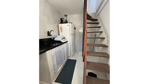 a small kitchen with a staircase and a refrigerator at Pé na areia Geriba Buzios 2 in Búzios