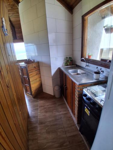 eine kleine Küche mit Spüle und Herd in der Unterkunft Bangalô Pé na Areia in Imbituba