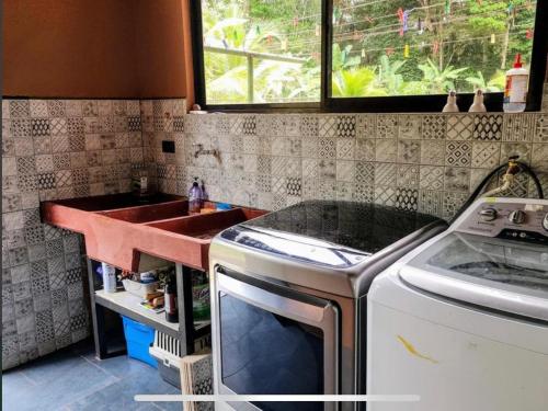 a kitchen with a sink and a washing machine at Paseo de Damitas in Quepos