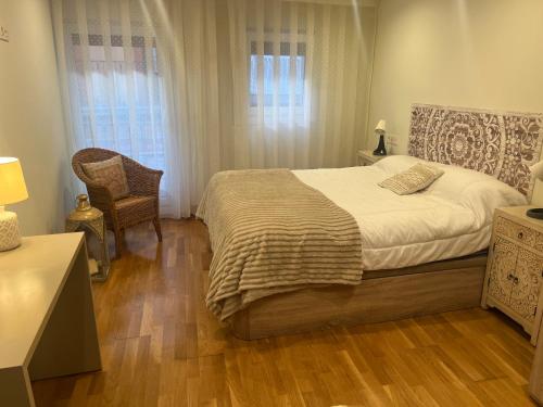a bedroom with a bed and a chair and a window at Casa del bienestar in Bermeo