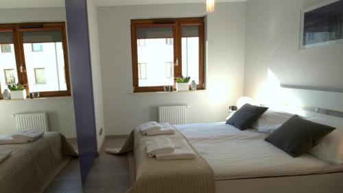 a bedroom with a large bed and two windows at IRS ROYAL APARTMENTS Apartamenty IRS Copernicus in Gdańsk