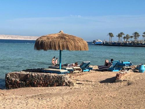 a group of people laying in chairs under an umbrella on the beach at Tiba Golden Resort in Hurghada