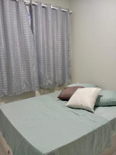 ein Bett mit zwei Kissen vor einem Fenster in der Unterkunft Flat Coqueirinho in Conde