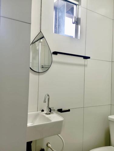 ein weißes Badezimmer mit Waschbecken und Spiegel in der Unterkunft Flat Coqueirinho in Conde