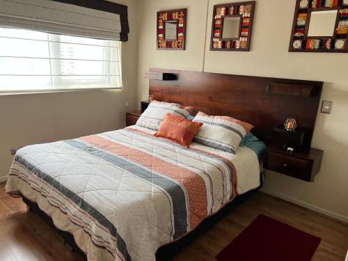 una camera da letto con un letto grande con testiera in legno di Departamento en Centro de Temuco a Temuco