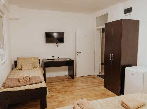 a small room with a desk and a bedroom at Gallus Inn in Aleksinac