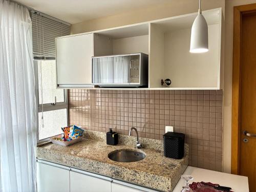 una cucina con lavello e microonde di Flat no Centro de Campo Grande a Campo Grande