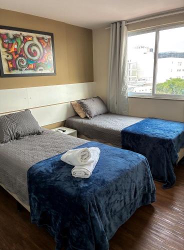 a hotel room with two beds and a window at Flat no Centro de Campo Grande in Campo Grande