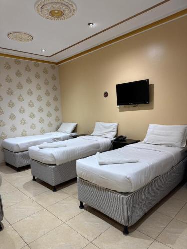 ein Zimmer mit drei Betten und einem Flachbildfernseher in der Unterkunft Jazirat Al Balad in Muzdalifah