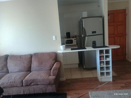 ein Wohnzimmer mit einem Sofa und eine Küche mit einem Kühlschrank in der Unterkunft M&L departamento in Limache
