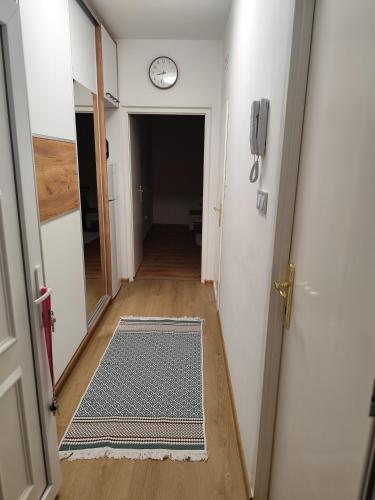 a hallway with a clock on the wall and a door at Tímea Apartman Pécs in Pécs