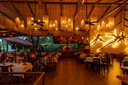 un ristorante con tavoli, sedie e lampadari di Maquenque Lodge a Boca Tapada