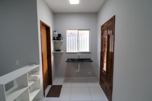 een hal met een badkamer met een wastafel en een deur bij Casa-Quarto Parnaíba in Parnaíba