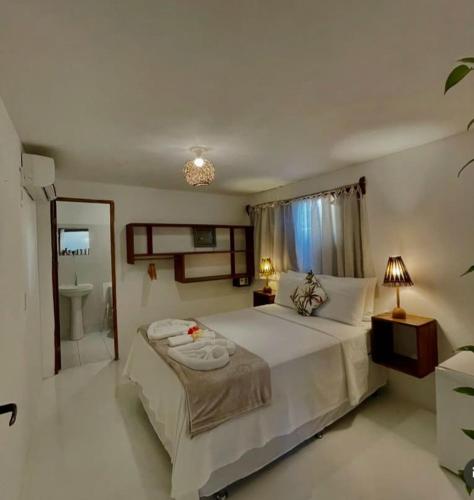 a bedroom with a large bed and a bathroom at Pousada Lumawê Caraíva in Porto Seguro