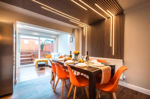 a dining room with a table and orange chairs at Hot Tube&Private Driveway&11 Guests Family&Contractors Bedford in Bedford