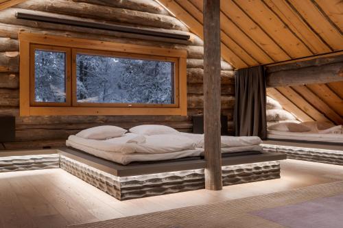 a bed in a log cabin with a window at Kelokurki - The Luxury Lodge Where Serenity Meets the Northern Lights in Levi