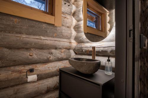 a bathroom with a stone sink and a wooden wall at Kelokurki - The Luxury Lodge Where Serenity Meets the Northern Lights in Levi